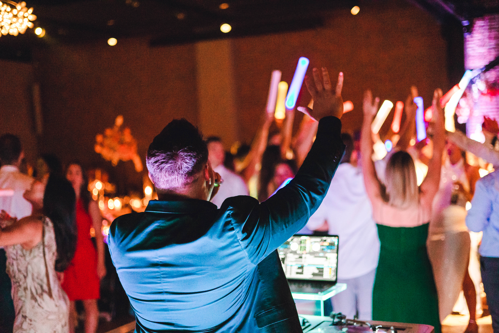 Nick Spinelli with his arm raised as the whole dance floor lifts glow sticks