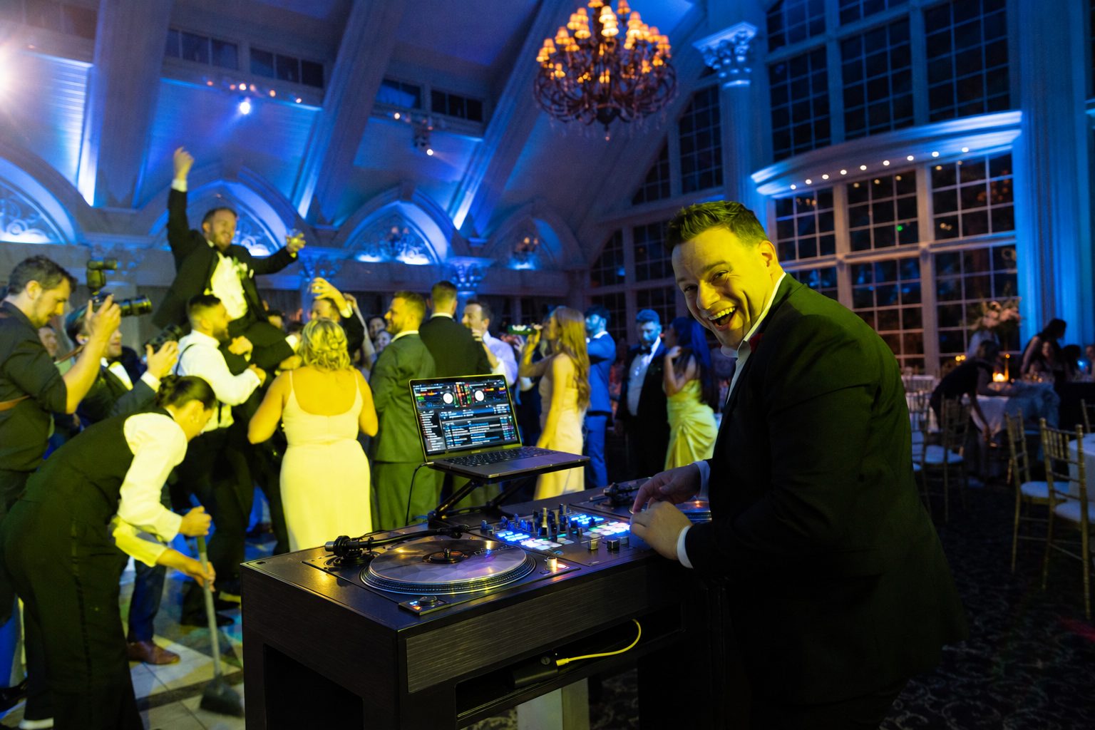 Nick Spinelli smiling behind the decks as a packed ballroom dances