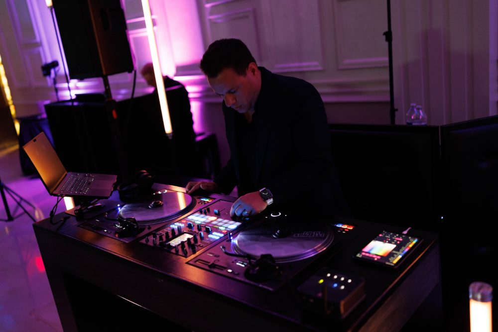 Nick Spinelli mixing behind the decks under purple uplighting